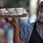 masked service at a pub holding a tray of drinks