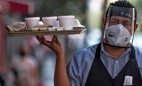 masked service at a pub holding a tray of drinks