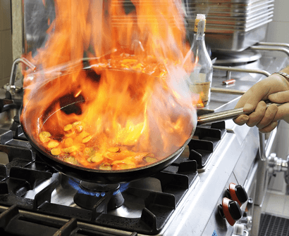 Pans on gas stove cooking food using a bunch of fire